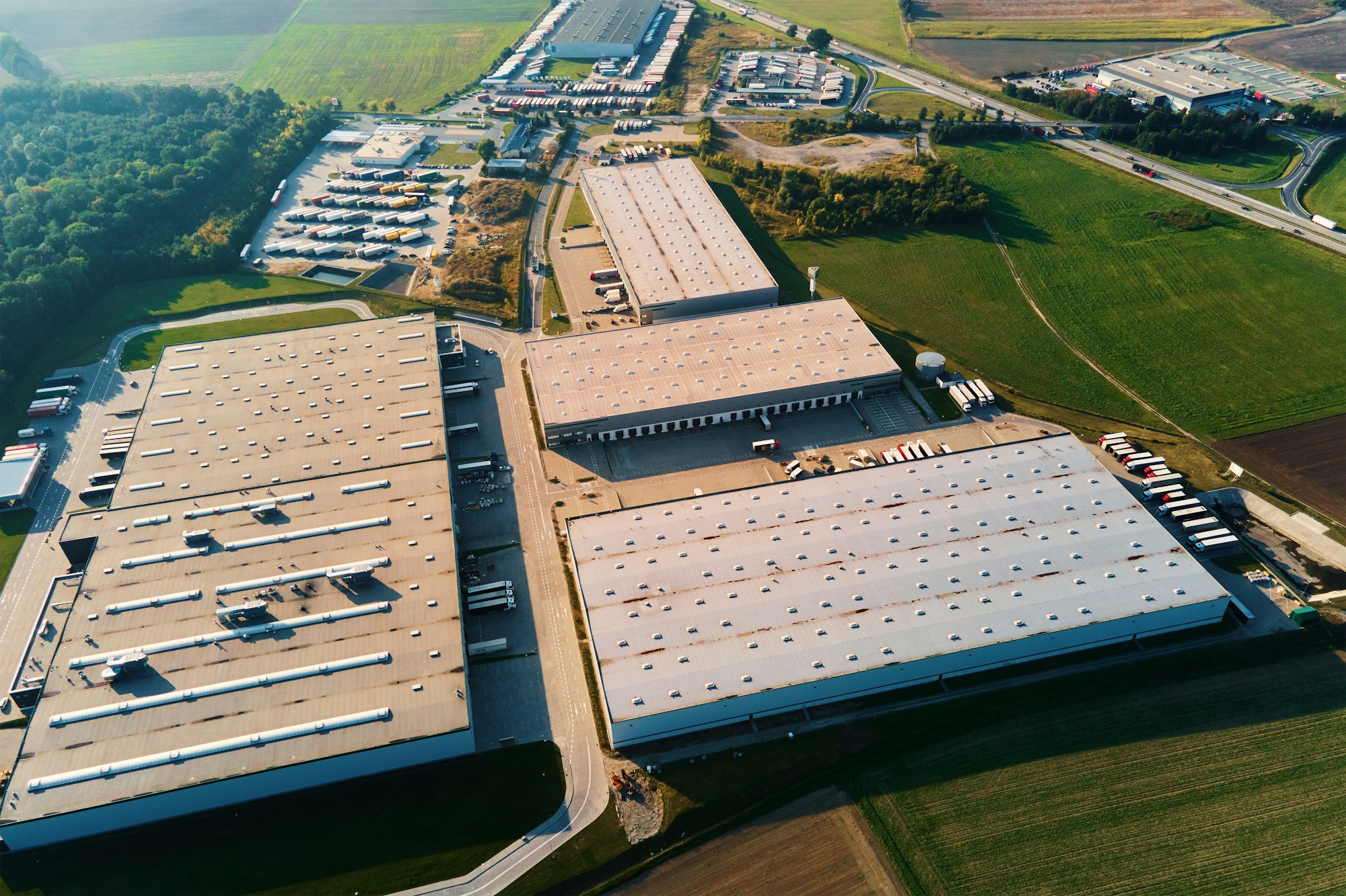 Factory warehouse with parked semi trucks, aerial view